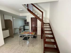 拉巴拉德納聖米格爾的住宿－Casa ao lado da praia，一间带玻璃桌和楼梯的用餐室