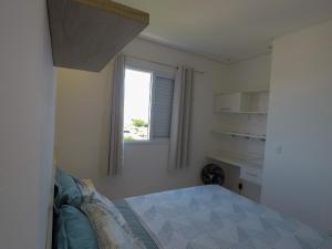 um pequeno quarto com uma cama e uma janela em Apê aconchegante e seguro em Salto