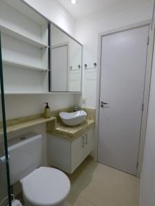 uma casa de banho com um WC branco e um lavatório. em Apê aconchegante e seguro em Salto