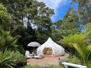 a white tent in the middle of a garden at Belle Glamping by the Sea in Katikati