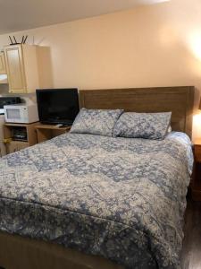 a bedroom with a bed with a blue comforter and a television at Shady Willow Guest House -Coach house & Privet Small Compact Rooms with separate entrance in Chilliwack