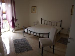 a bedroom with a bed and a chair and a window at Casa veneto in Montalbano Ionico