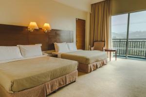 Habitación de hotel con 2 camas y balcón en Heritage Hotel Cameron Highlands en Cameron Highlands
