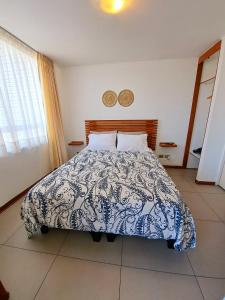 ein Schlafzimmer mit einem Bett mit einer blau-weißen Bettdecke in der Unterkunft Céntrico y cómodo departamento in Concepción + 8 Fotos