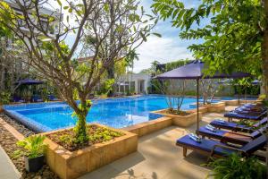 a pool at a hotel with blue lounge chairs and a tree at Koulen Hotel in Siem Reap