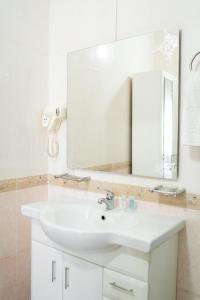 a bathroom with a white sink and a mirror at Aktau Airport Hotel in Aktau