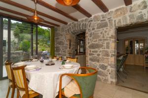 a dining room with a table and a stone wall at Villa Salvia with pool in Ružići