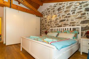a white bed in a room with a stone wall at Villa Salvia with pool in Ružići +35 photos