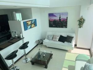 uma sala de estar com um sofá branco e uma mesa de centro em Beautiful 1 Br Loft Apartment em Manizales