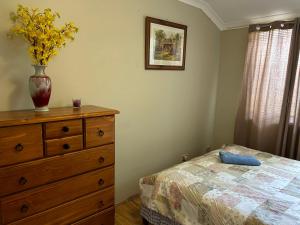 - une chambre avec une commode et un vase orné de fleurs dans l'établissement Lovely house in canning vale, à Perth