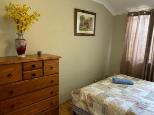 um quarto com uma cómoda e um vaso com flores em Lovely house in canning vale em Perth
