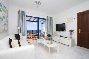 a living room with a white couch and a tv at Harbour Lights in Puerto del Carmen