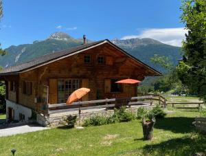 ein Holzhaus mit zwei orangenen Sonnenschirmen davor in der Unterkunft Chalet Albarose - Vercorin in Vercorin