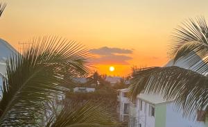 un coucher de soleil sur une ville avec des bâtiments et des palmiers dans l'établissement Bel appart Étang salé La réunion, à Étang-Salé les Bains