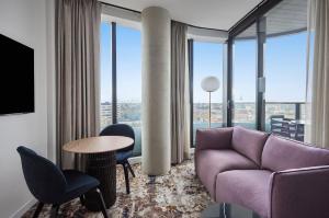 a living room with a purple couch and a table and chairs at Adina Apartment Hotel Melbourne, Pentridge in Melbourne