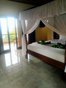 - une chambre avec un lit à baldaquin dans l'établissement Coral Bay Bungalows Amed Bali, à Amed