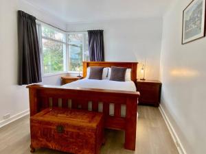 1 dormitorio con cama de madera y ventana en Sunny Beach Holiday Home 80, en Kingston Beach