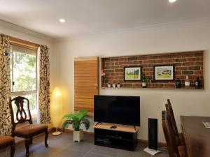 a living room with a tv and a brick wall at Sunset Hues -Enjoy Peace & Nature in Norton Summit