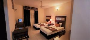 Habitación de hotel con 2 camas y TV en Ras Dika Hotel, en Yibuti