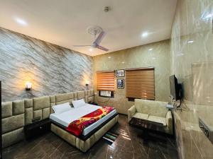 a bedroom with a bed and a couch and a television at Hotel Majestic in Kolkata