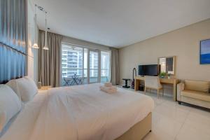een slaapkamer met een groot wit bed en een woonkamer bij Luxurious studio Hotel Amenities in Dubai