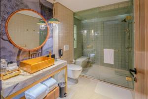 a bathroom with a sink and a toilet and a mirror at Hotel Indigo Bangkok Wireless Road, an IHG Hotel in Bangkok