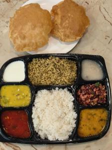 a tray of food with rice and bread on a plate at Yashaswi Comforts in Mysore