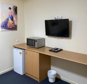 a desk with a microwave and a television on a wall at Echuca Motel in Echuca