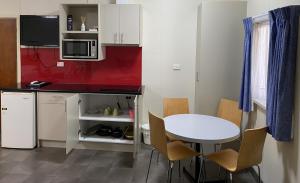 a small kitchen with a white table and a red wall at Echuca Motel in Echuca