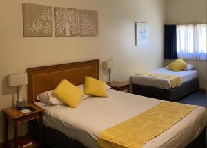 Habitación de hotel con 2 camas con almohadas amarillas en Echuca Motel, en Echuca