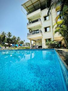 a large blue swimming pool in front of a building at Anant Resort Nagaon Beach Walking Distance 2min Alibaug in Alibaug