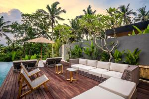 een patio met een witte bank en stoelen op een houten terras bij Villa Livia by BaliSuperHost in Ubud