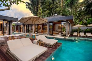 een buitenzwembad met stoelen en parasols naast een huis bij Villa Livia by BaliSuperHost in Ubud
