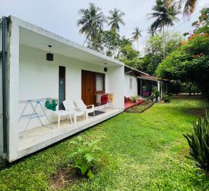 a house with a green yard with chairs on the porch at The Loft in Midigama East