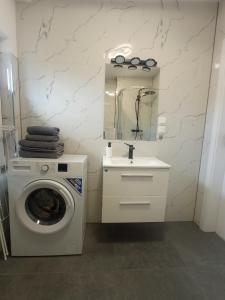 a white bathroom with a washing machine and a sink at Apartament Wolności in Jelenia Góra