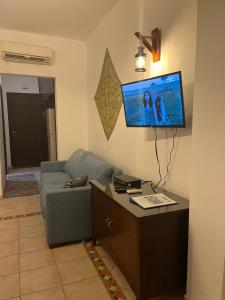 ein Wohnzimmer mit einem Sofa und einem TV an der Wand in der Unterkunft Deep Ashri in Marsa Alam City