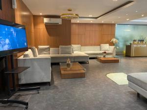 sala de estar con sofás y TV de pantalla plana. en Deluxe Suites Skyview with Infinity Pool, en Sunggal