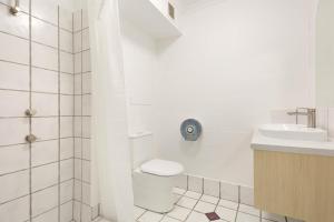 a white bathroom with a toilet and a sink at Abode Mooloolaba, Backpackers & Motel rooms in Mooloolaba