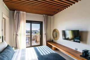 1 dormitorio con 1 cama y TV en la pared en Uma Ray Suites, en Fira