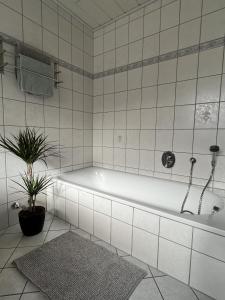 uma casa de banho branca com uma banheira e uma planta em Ferienwohnung Moselzeit em Alken