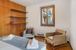 a bedroom with two chairs and a bed and a window at Casa Rossella in Bormio
