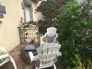 two white chairs sitting in a garden with flowers at Studio paisible et balnéo in Vezin-le-Coquet