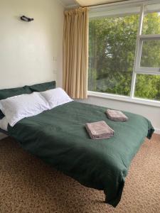 um quarto com uma cama verde com duas toalhas em Peppermint Retreat Taroona em Taroona