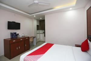 - une chambre avec un lit et une télévision murale dans l'établissement Kamat Inn, à Bankipur