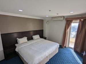 a bedroom with a large bed and a large window at Rest Park Hotel in Dammam
