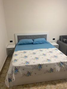 1 dormitorio con 1 cama con edredón azul y blanco en Cappuccino City Center Apartment en Lezhë