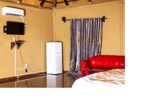 una camera con un letto, un divano rosso e una TV di MSC Hotel Otjiwarongo a Otjiwarongo