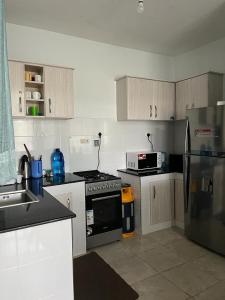 a kitchen with a stove top oven and a refrigerator at Zoe Homes 1br and 2br Apartment Greypoint 406 in Kericho