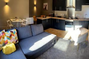 a living room with a blue couch and a kitchen at Luxury In Loughborough in Loughborough