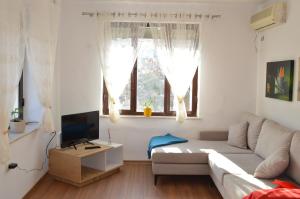 a living room with a white couch and a television at RH Tirana Center in Tirana